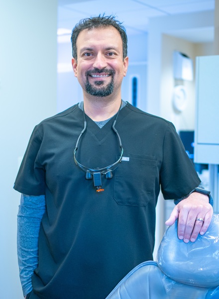 Dentist standing beside a treatment chair in a modern dental office in Reston, VA